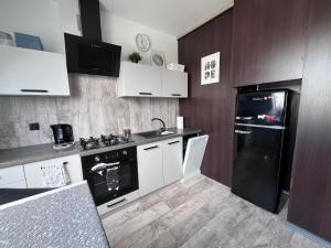 a kitchen with white cabinets and a black refrigerator at Apartament Culica Września in Września