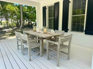 un tavolo e sedie in legno su un portico di Hibiscus Hill Cricket Pavilion - retreat near Pink Sand Beach cottage a Harbour Island