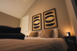 a bedroom with a bed with two pictures on the wall at Tiny House Hellendoorn in Haarle +41 photos