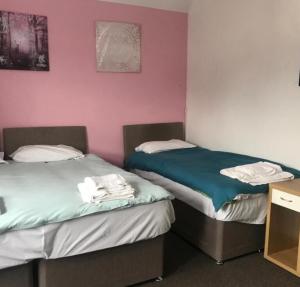two beds in a room with pink walls at Stay Heathrow in Hounslow