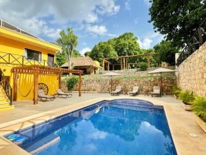 ein Swimmingpool in einem Garten mit einem Haus in der Unterkunft Hotel Rinconada del Convento - Izamal in Izamal