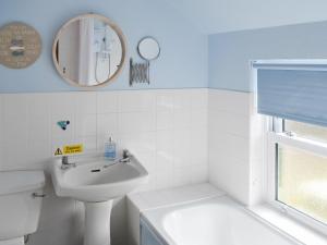 ein weißes Badezimmer mit Waschbecken und Spiegel in der Unterkunft Willow Cottage in Newlyn East