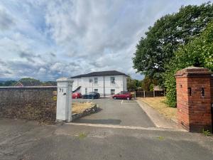 a parking lot with a white house and a brick wall at THE SPRINGFIELD SUITE - ONE BEDROOM APARTMENT - KIDDERMINSTER CENTRAL - SLEEPS 3 GUESTS - PARKING INCLUDED - WEST MIDLANDS SAFARI PARK LOCATIOn in Kidderminster