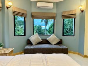 a bedroom with a bed and two windows and a couch at Mimi Pool Villa Chiangmai in Chiang Mai +32 photos