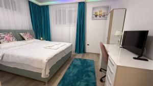 ein Schlafzimmer mit einem Bett und einem Schreibtisch mit einem Fernseher in der Unterkunft Mara Stefania Apart Hotel Deluxe in Oradea