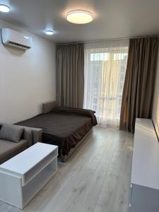 a bedroom with a bed and a couch and a window at ЖК Парус, 9-1 in Chornomorsk