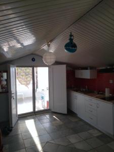 a kitchen with white cabinets and a large sliding glass door at Amfialos in Skala Kallirakhis