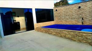 帕尔马斯Conforto e Lazer! Casa com Piscina e 3 Quartos的砖墙中的一个大型蓝色游泳池