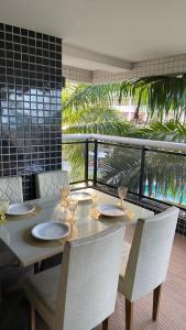 a dining table with chairs and a balcony with palm trees at Hotel Platinum - Landscape Luxo - in Fortaleza