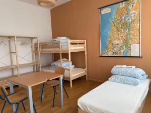 a room with bunk beds and a table and a desk at Emmas Hostels Duisburg in Duisburg