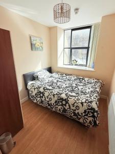 a bedroom with a bed with a black and white comforter at Double Bed Apartment Bradford City Center in Bradford