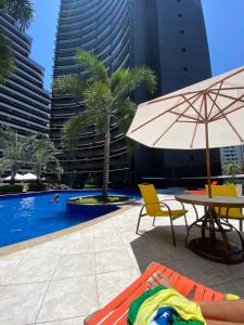 a pool with a table and an umbrella and chairs at Hotel Platinum - Landscape Luxo - in Fortaleza