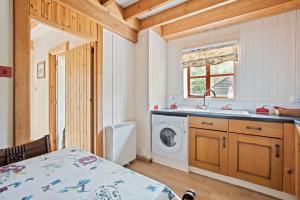 a kitchen with a sink and a washing machine at Charming thatched cottage near New Forest in Breamore +12 photos