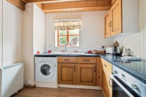 a kitchen with a washing machine and a sink at Charming thatched cottage near New Forest in Breamore