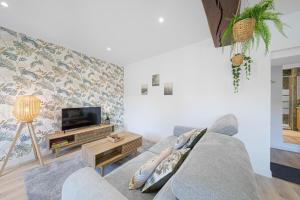a living room with a couch and a tv at La Canopée NATURE & ESPRIT CHIC Neuf et Parking facile in Ladoix Serrigny