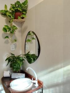 Un baño con lavabo, espejo y plantas. en Casa Ilhabela 2 centro a 5 minutos, en Ilhabela