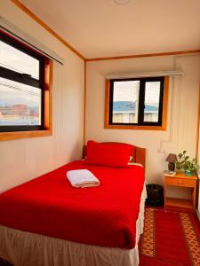 a red bed in a room with two windows at Hostal B&B Coastal Natales in Puerto Natales +48 photos