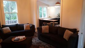 Una sala de estar con dos sofás y una cocina. en Clutha Gold Cycle Trail Cottage 4 bedroom Roxburgh, en Roxburgh
