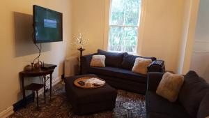 Una sala de estar con un sofá y un televisor de pantalla plana. en Clutha Gold Cycle Trail Cottage 4 bedroom Roxburgh, en Roxburgh