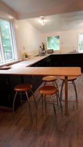 Una cocina con una mesa de madera y dos taburetes. en Clutha Gold Cycle Trail Cottage 4 bedroom Roxburgh, en Roxburgh