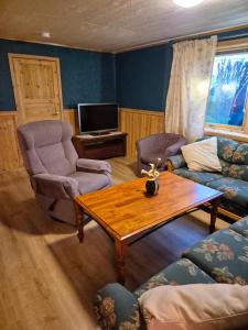 ein Wohnzimmer mit Tisch und Stühlen und einem Fernseher in der Unterkunft The Blue house apartment in Andøya