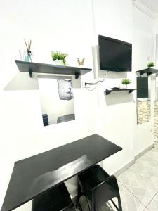 ein Wohnzimmer mit einer schwarzen Bank und einem TV in der Unterkunft Ondas & Sol in São Vicente + 7 Fotos