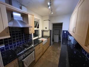 a kitchen with wooden cabinets and a stove top oven at 4 Double Bedroom House with Private Garden and Own Entrance in Henwick