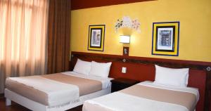 two beds in a hotel room with yellow walls at Hotel Benedicta in Mexico City