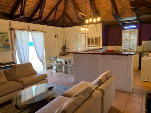 a kitchen and living room with a couch and a table at Villa d'hôtes Pointe Larose in Le Robert