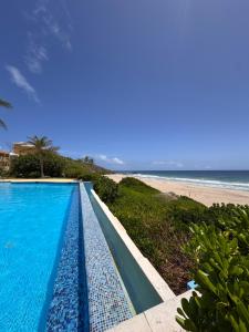 a swimming pool next to a beach with the ocean at Apartamento Cimarron Suites in La Mira