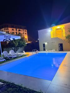 a pool at night with chairs and an umbrella at La Piscina in Shkodër