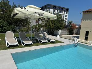 a group of chairs and an umbrella next to a pool at La Piscina in Shkodër