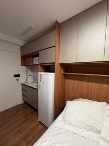 ein Schlafzimmer mit einem weißen Bett und einer Küche in der Unterkunft Studio Apartamento no Morumbi próximo ao Estádio Morumbi estação de ônibus metrô e shopping in São Paulo + 9 Fotos