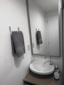 ein weißes Badezimmer mit Waschbecken und Spiegel in der Unterkunft Studio Apartamento no Morumbi próximo ao Estádio Morumbi estação de ônibus metrô e shopping in São Paulo