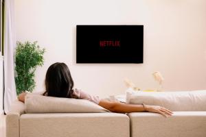 eine Frau sitzt auf einer Couch und sieht fern in der Unterkunft VIOLA by Elegant Hospitality - near Waterway Mall in Kairo