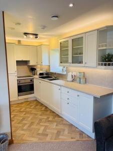 a kitchen with white cabinets and a wooden floor at Peedie Orkney Cottage in Orkney