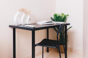 un bureau noir avec une chaise, des vases et des livres dans l'établissement VIOLA by Elegant Hospitality - near Waterway Mall, au Caire