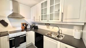 a kitchen with white cabinets and a sink at Romslig leilighet med 2 soverom - GRATIS PARKERING in Tromsø