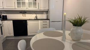 a white kitchen with a table and a vase with a plant at Romslig leilighet med 2 soverom - GRATIS PARKERING in Tromsø