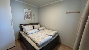 a small bedroom with a bed with pillows on it at Romslig leilighet med 2 soverom - GRATIS PARKERING in Tromsø +8 photos