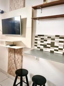 a room with two stools and a tv on a wall at Mar à porta in São Vicente