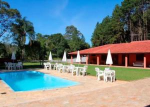 a resort with a pool and chairs and a building at Hotel Terras Altas in Itapecerica da Serra