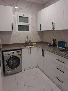 a kitchen with white cabinets and a washing machine at 1 room apartment Delta in Sharm El Sheikh