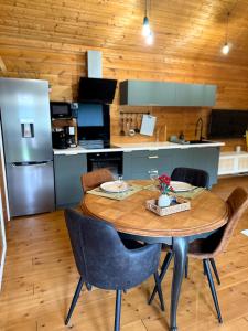 eine Küche mit einem Tisch mit Stühlen und einem Kühlschrank in der Unterkunft "Kota coeur de bois" Chalet en bois au domaine de l'Aa in Bourbourg
