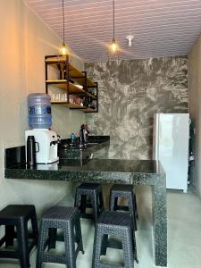a kitchen with a counter with stools and a refrigerator at Chalé 2 - Próximo à igreja do céu in Viçosa do Ceará +6 photos