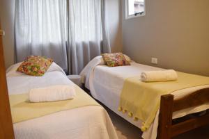 a room with three beds with towels on them at Hotel Cabañas Aparts Tierra de Glaciares in El Calafate