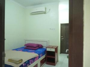 a small bedroom with a bed and a mirror at Nadyah Syariah Homestay in Ketapang