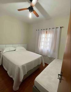アチバイアにあるLinda casa em condominioのベッド2台と天井ファン付きの寝室