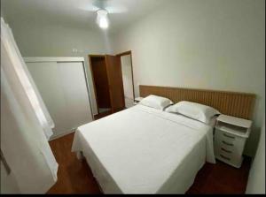 アチバイアにあるLinda casa em condominioの白いベッドとナイトスタンドのある寝室 +5枚の写真
