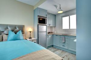 Malaga Lodge Studio في مالقة: غرفة نوم زرقاء مع سرير ومطبخ